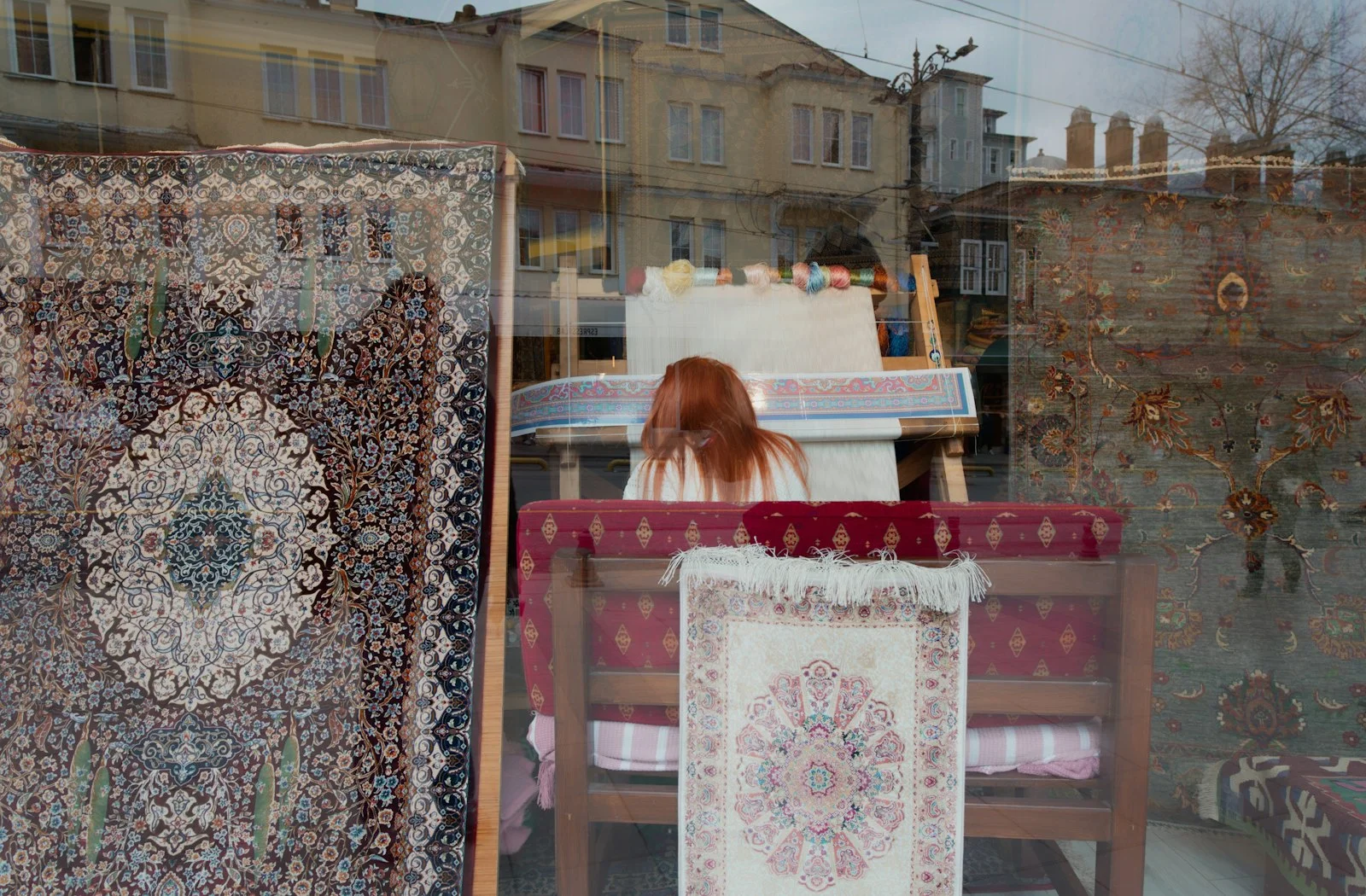 A woman with red hair weaving inside a carpet store